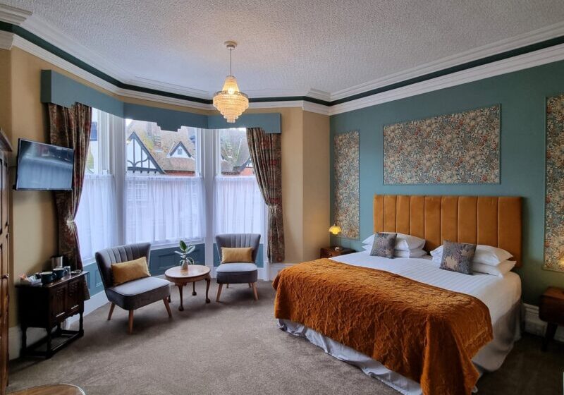 Bright corner of a Cavendish bedroom with armchairs by the window