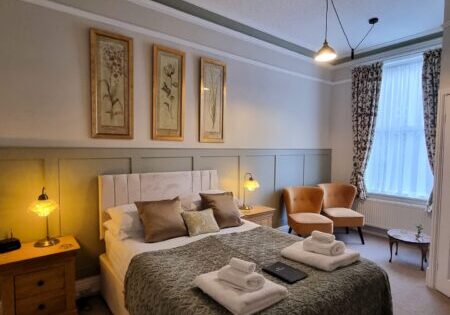 King bedroom with tall windows and folded towels